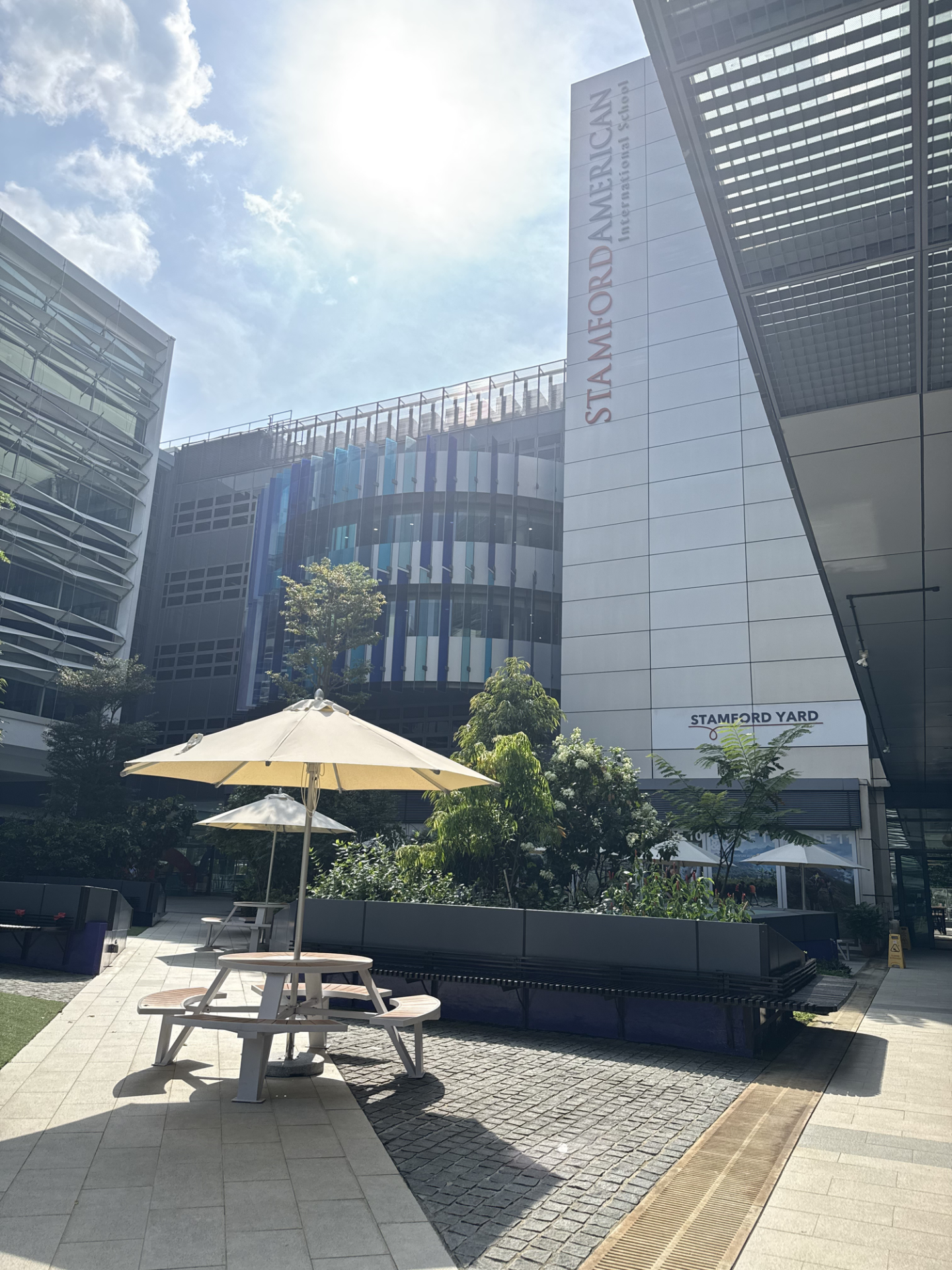 STAMFORD AMERICAN International Schoolと表示された建物と、パラソル付きのテーブル