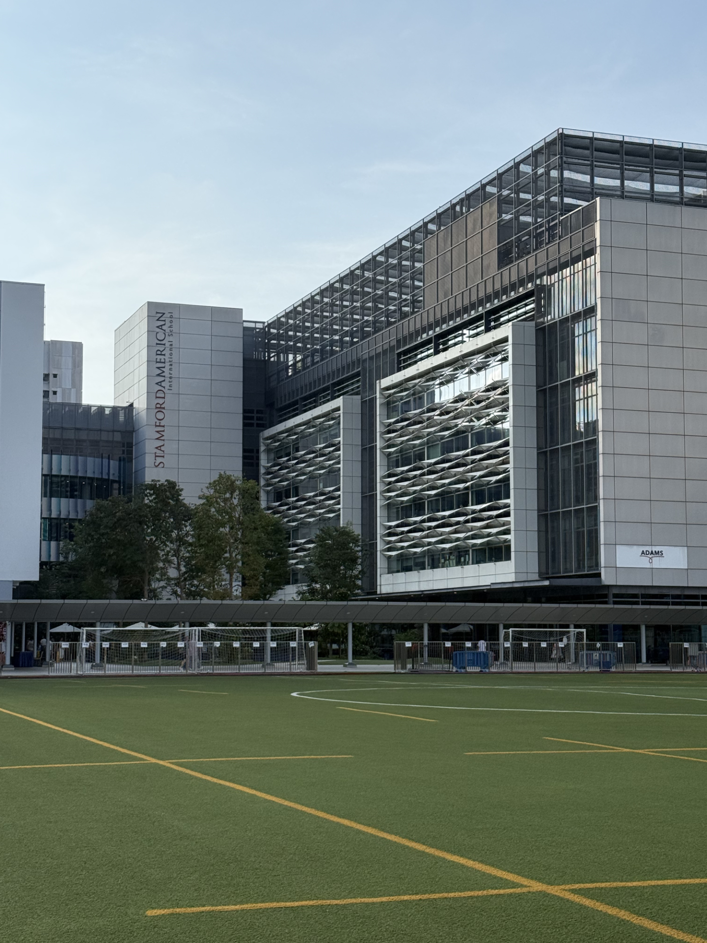 人工芝のグラウンドとゴール、奥にStamford American International Schoolと記された建物