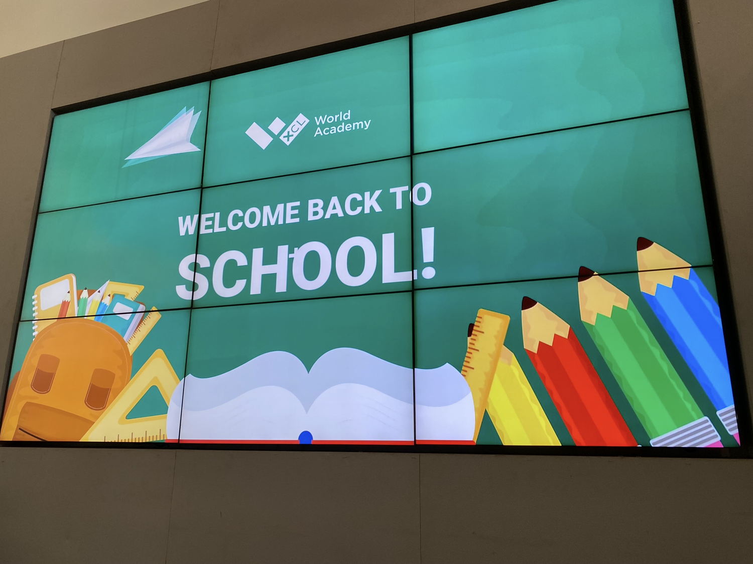 「WELCOME BACK TO SCHOOL!」と表示された壁掛けの大型ディスプレイ