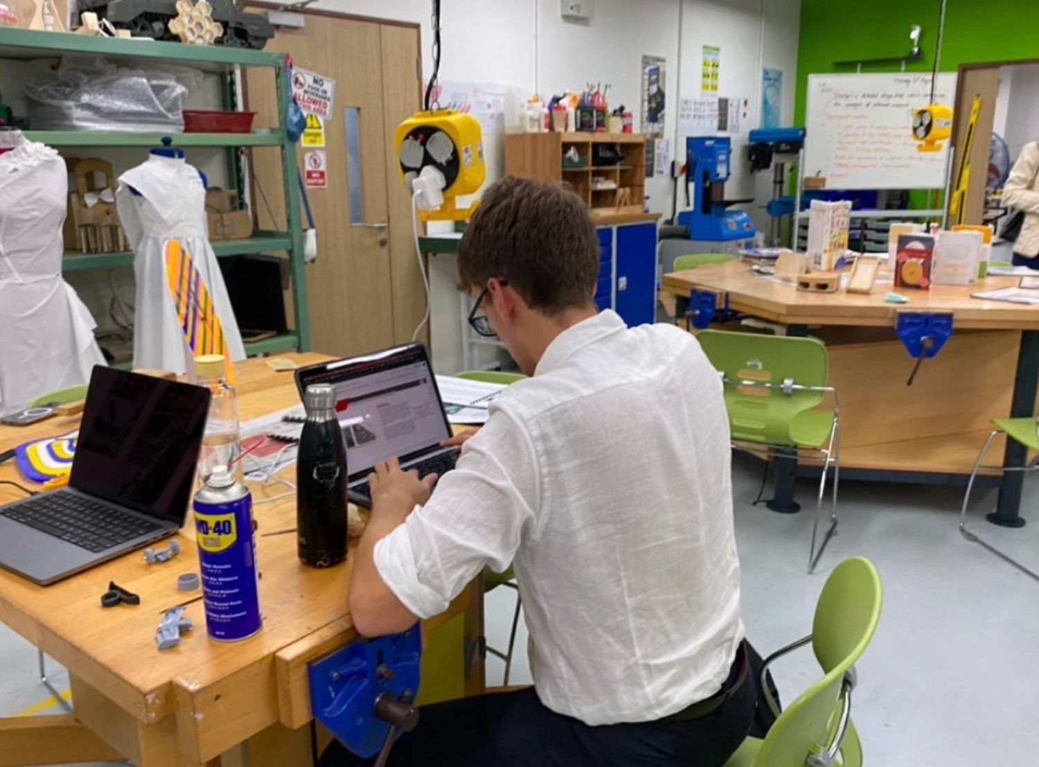 万力のついた木製作業台が並ぶ部屋でノートパソコンを操作する人物